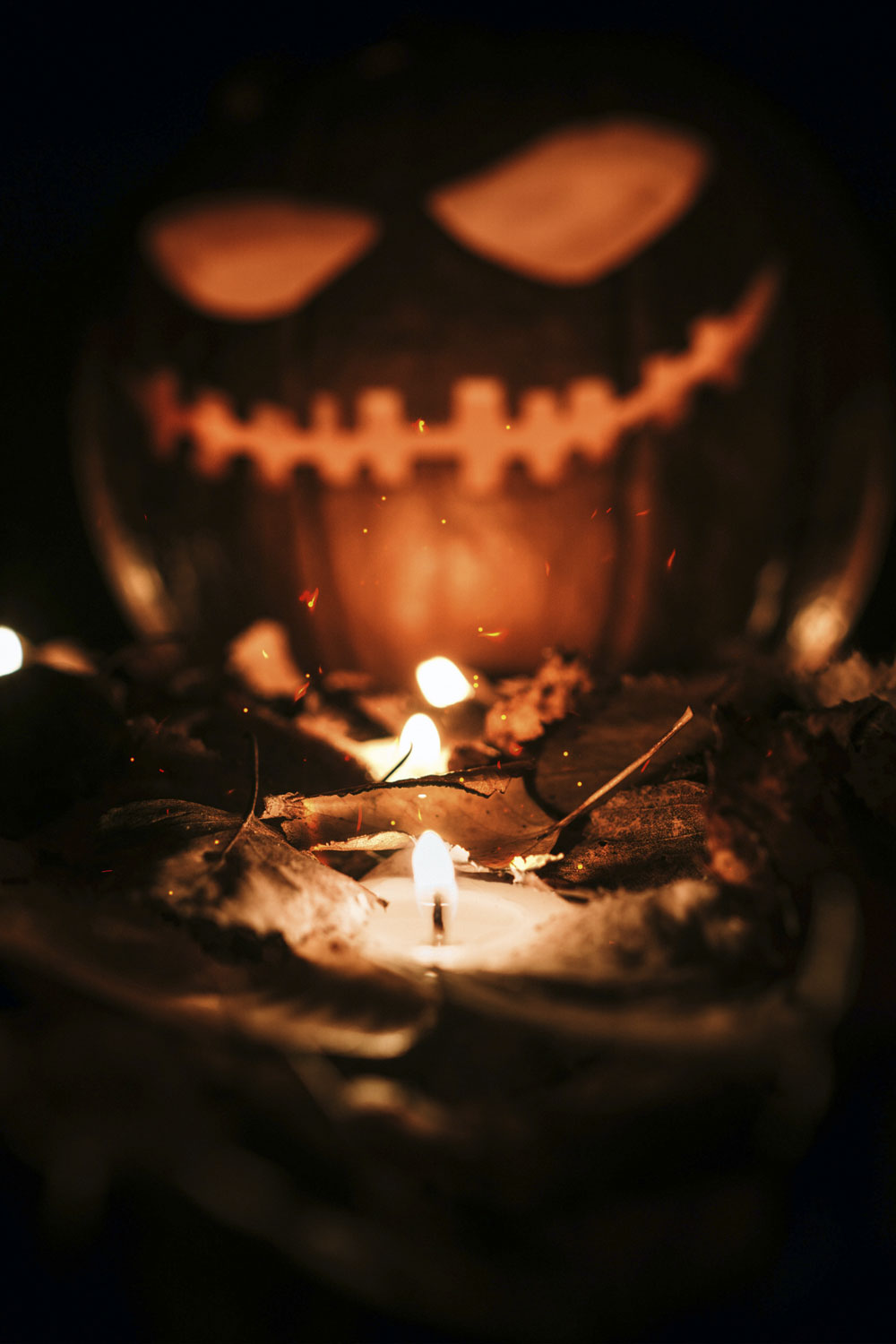 Out of focus pumpkin with a candle in front.