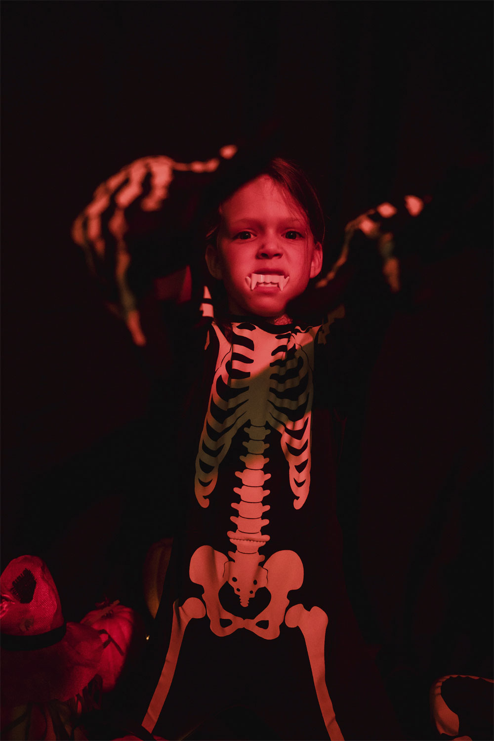 child dressed as a skeleton lit by red ambient light
