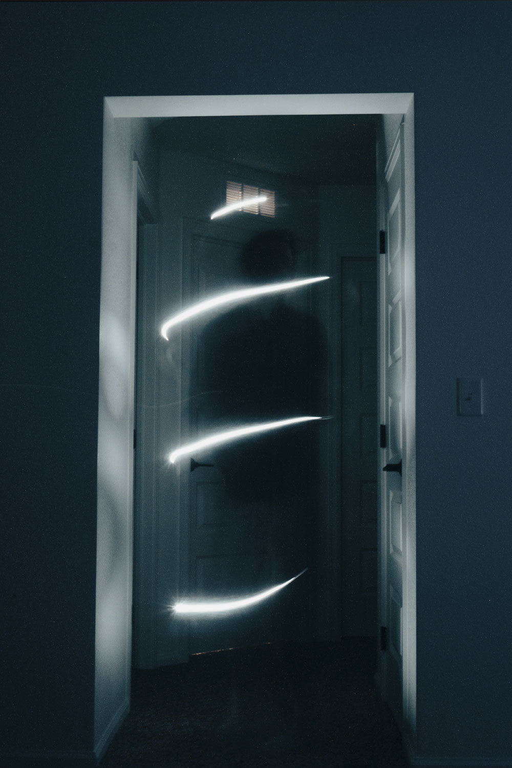 A outline of a person in a doorway painted in light